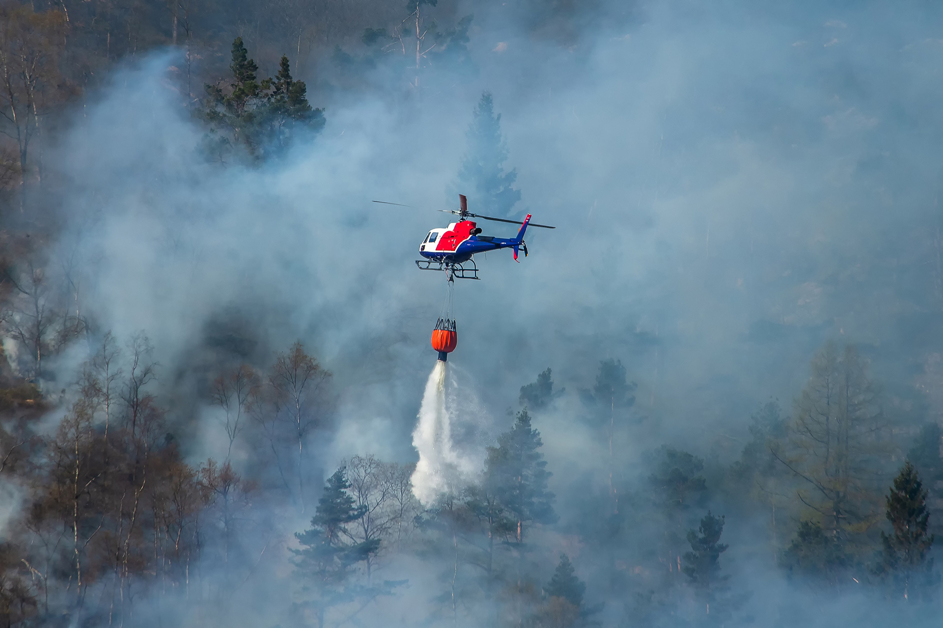 Aerial view of a helicopter extinguishing a wildfire in a remote location